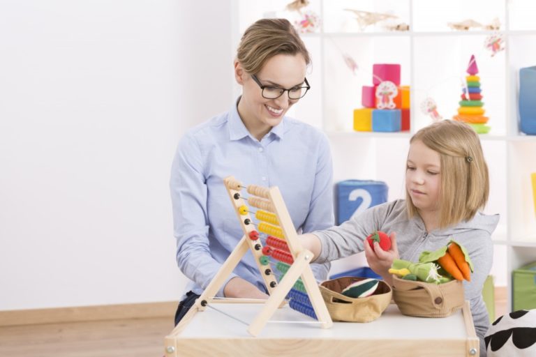 Woman helping young girl count with abacus