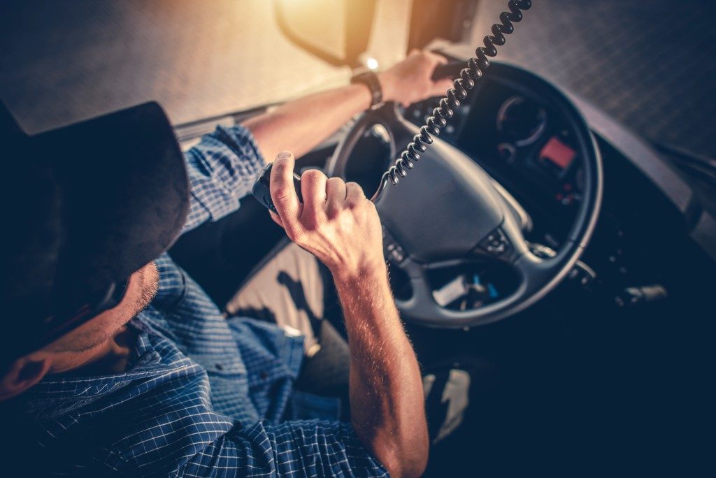 Man behid the truck's stearing wheel using the radio