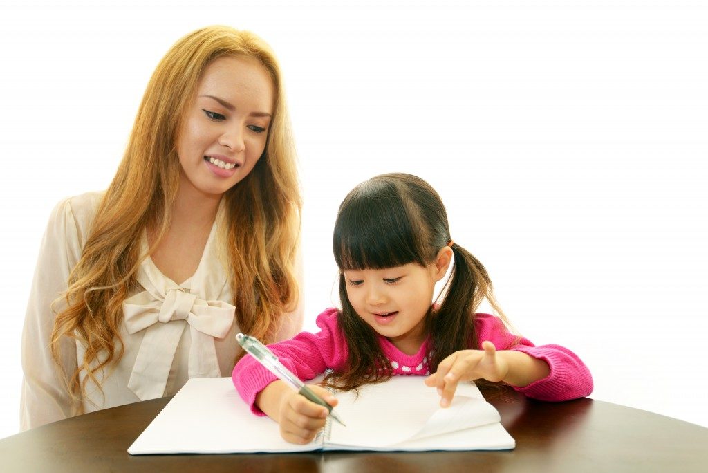 Little girl studying English with her teacher