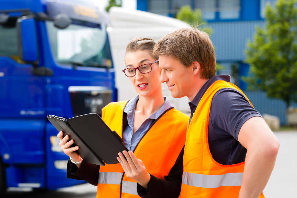 a businesswoman sharing records to a driver both wearing safety vests