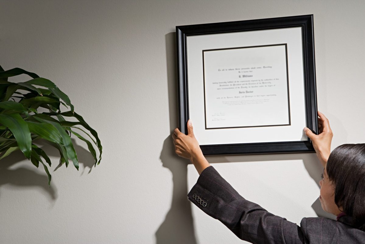 woman hanging a framed certificate